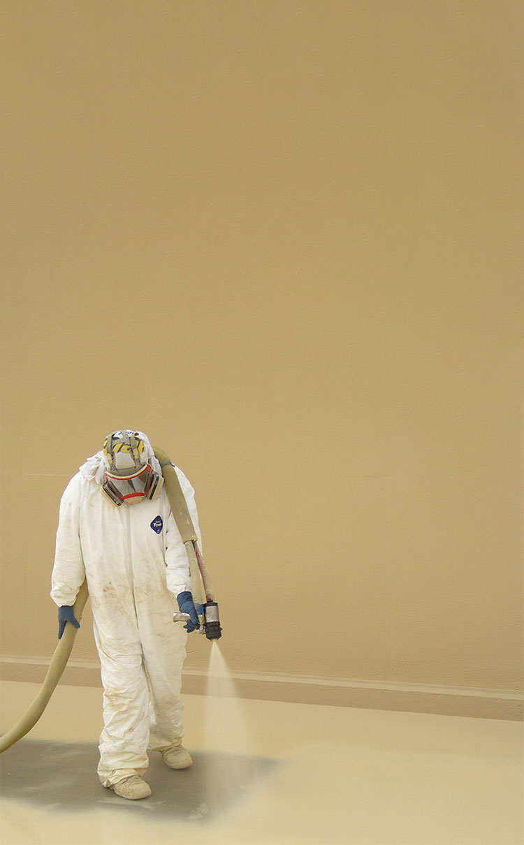Man in protective gear spraying coating